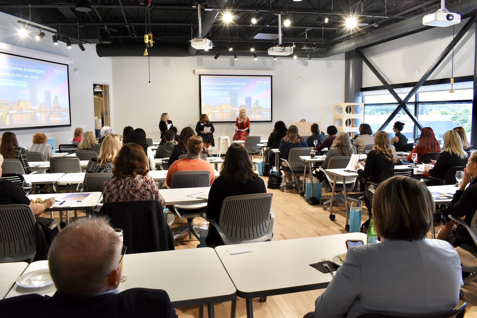 A room full of people watching a slideshow presentation